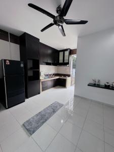 une cuisine avec des armoires noires et un ventilateur de plafond dans l'établissement Homestay, à Sitiawan