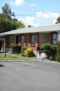 une maison en briques rouges avec un toit blanc dans l'établissement Ascot Lodge Motel, à Hamilton