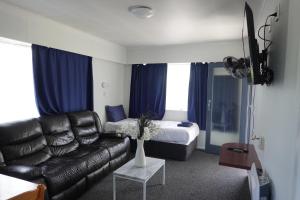 - un salon avec un canapé et un lit dans l'établissement Ascot Lodge Motel, à Hamilton