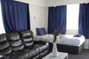 a living room with a leather couch and a bed at Ascot Lodge Motel in Hamilton