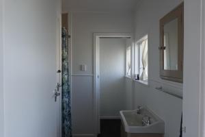 a white bathroom with a sink and a mirror at Ascot Lodge Motel in Hamilton