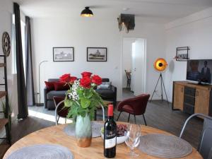ein Wohnzimmer mit einem Tisch mit einer Flasche Wein und Rosen in der Unterkunft Old town view in the Ohlerich warehouse in Wismar