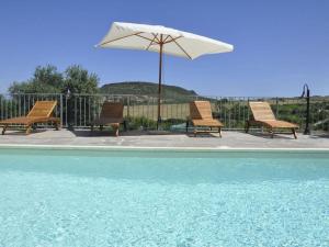 eine Gruppe Stühle und ein Sonnenschirm neben einem Pool in der Unterkunft Lubagnu Vacanze in Castelsardo