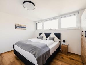 a bedroom with a large bed with white walls and windows at Holiday apartment 3 in the holiday home Sandra in Hörbranz