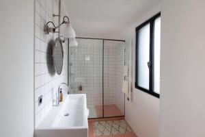 a white bathroom with a sink and a shower at Bright & Eco-Friendly Wooden Home, A Peaceful Retreat Near Paris in Montreuil