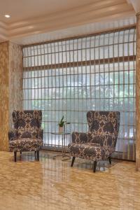 Regent Hotel Andheri في مومباي: كرسيين وطاولة في غرفة مع نوافذ