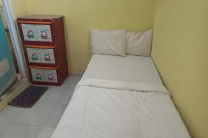 Un pequeño dormitorio con una cama blanca y un tocador en SPOT ON 93886 Kost Zalfa Amalia Syariah, en Tegal