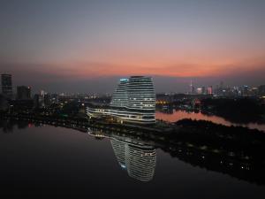 un gran edificio con su reflejo en el agua en Vignette Collection The Xanadu Guangzhou, an IHG Hotel, en Guangzhou