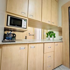 a kitchen with wooden cabinets and a microwave and plants at أستديو فندقي ديلوكس in Jazan