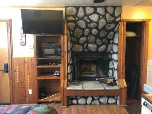 uma sala de estar com uma lareira de pedra e uma televisão em Creek Runner's Lodge em Big Bear Lake