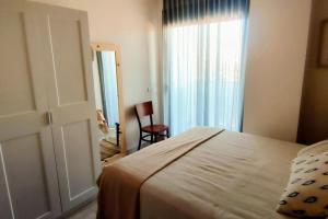 a bedroom with a bed and a window and a chair at L'Ampolla, sol y mar in L'Ampolla