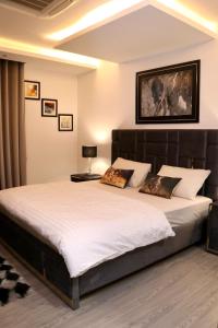 a bedroom with a large bed with white sheets at Centaurus Mall & Residency Luxury Apartments in Islamabad