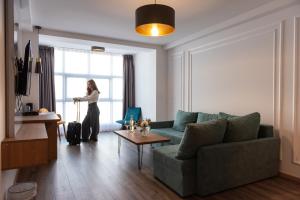 a woman standing in a living room looking out the window at Dishli Hotel & Spa in Struga