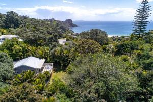 Una vista aérea de una casa con el océano al fondo. en Nikau Cottage - Palm Beach Holiday Home, en Palm Beach