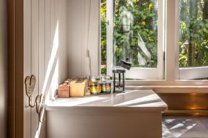 Un mostrador de cocina con una ventana con frascos. en Nikau Cottage - Palm Beach Holiday Home, en Palm Beach