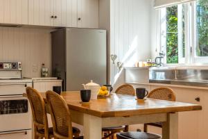 Una cocina con una mesa con sillas y un refrigerador. en Nikau Cottage - Palm Beach Holiday Home, en Palm Beach 15 fotos más
