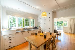 Una cocina con una mesa de madera y un comedor. en Nikau Cottage - Palm Beach Holiday Home, en Palm Beach