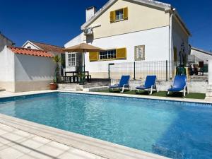 una piscina con 2 sillas azules y una casa en Casa Vila Sao & Pompeia, en Sesimbra