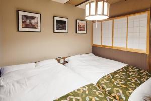 a bedroom with two white beds and pictures on the wall at 組紐の間 in Tokyo