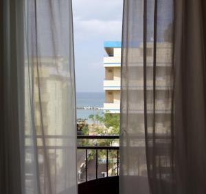 une fenêtre avec vue sur un bâtiment et l'océan dans l'établissement Hotel Anita, à Gatteo a Mare