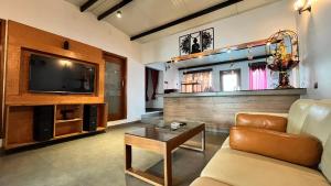 een woonkamer met een bank, een tv en een tafel bij Mermaid Island Beach Resorts in Pondicherry