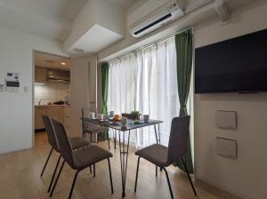 ein Esszimmer mit einem Tisch, Stühlen und einem TV in der Unterkunft ESLEAD HOTEL Namba South Ⅱ in Osaka
