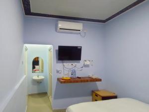 WatesにあるRedDoorz Syariah Near Stasiun Watesのベッド1台と壁掛けテレビが備わる客室です。