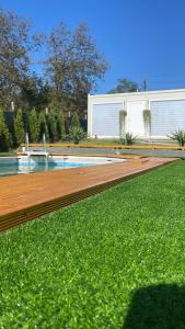 a swimming pool with a wooden deck and green grass at Vikendica Freedom in Požarevac