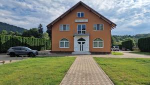 a house with a car parked in front of it at Pensiunea Hyperion Cormaia in Sîngeorz-Băi