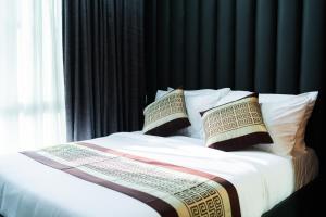 ein Schlafzimmer mit einem Bett mit Kissen und einem Fenster in der Unterkunft Shine Boutique Hotel in Tagum