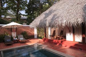 un complexe avec une piscine et un toit de chaume dans l'établissement Marari Beach Resort Alleppey- CGH Earth, à Alappuzha