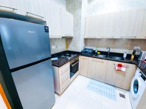 a small kitchen with a refrigerator and a sink at NA 303 Ansam Yas Island in Abu Dhabi