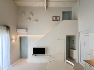 a white living room with a table and a tv at Ta Spitakia in Kos