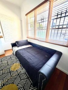 Bett in einem Zimmer mit einem großen Fenster in der Unterkunft Princes Cottage In Prahran, On Chapel St in Melbourne