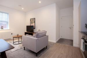 ein Wohnzimmer mit einem Stuhl und einem TV in der Unterkunft Modern 1 Bedroom Apartment in Bolton in Bolton