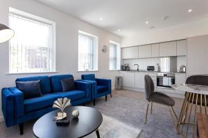 Fantastic 1 Bedroom Apartment in Bolton في بولتون: غرفة معيشة مع أريكة زرقاء ومطبخ