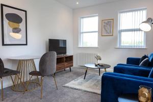 Fantastic 1 Bedroom Apartment in Bolton في بولتون: غرفة معيشة مع أريكة زرقاء وتلفزيون