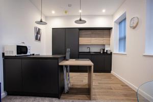 una cucina con armadi neri e tavolo in legno di Lovely Open Plan 1 Bedroom Apartment in Bolton a Bolton Altre 9 foto