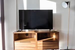 a flat screen tv sitting on a wooden entertainment center at Beautiful 2 bedroom apartment in a converted mill in Leeds