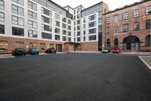 an empty parking lot in front of a large building at Beautiful 2 bedroom apartment in a converted mill in Leeds