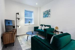 a living room with two green couches and a television at Fantastic 1 bedroom apartment in Bolton in Bolton