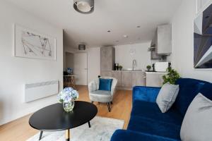 a living room with a blue couch and a table at 1 Bed Modern Apartment in a Converted Mill in Leeds