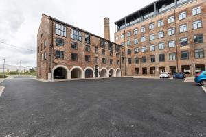 an empty parking lot in front of a brick building at 1 Bed Modern Apartment in a Converted Mill in Leeds