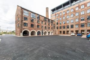 an empty parking lot in front of a brick building at 1 Bed Modern Apartment in a Converted Mill in Leeds