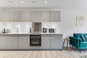 una cocina con armarios blancos y un sofá verde en Modern & Stylish 1Bed Flat in Central Birmingham, en Birmingham