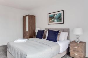 a bedroom with a large bed with blue pillows at Stunning 2br Flat in the Centre of Birmingham in Birmingham