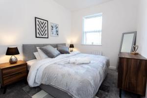 a bedroom with a large bed with a dresser and a mirror at Modern 1 Bedroom Apartment in Bolton in Bolton