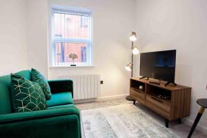 a living room with a green couch and a flat screen tv at Modern & Stylish 1 Bedroom Apartment in Bolton in Bolton