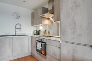 una cocina con electrodomésticos de acero inoxidable y fregadero en Lovely Riverside 2 Bed Apartment, en Leeds