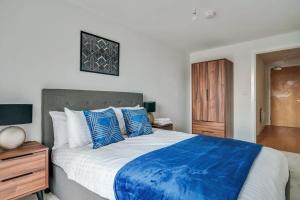 1 dormitorio con 1 cama grande con almohadas azules y blancas en Lovely Riverside 2 Bed Apartment, en Leeds